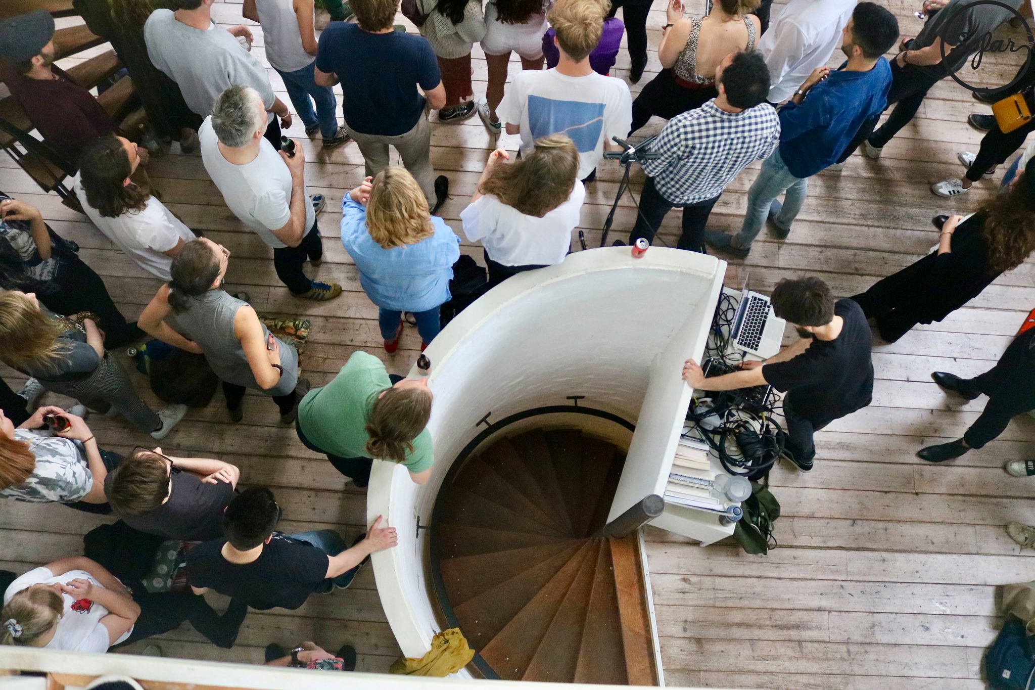 top view of a live audience at the concert with the spiral staircase in the middle and people leaning on the rails sound engineer standing next to it