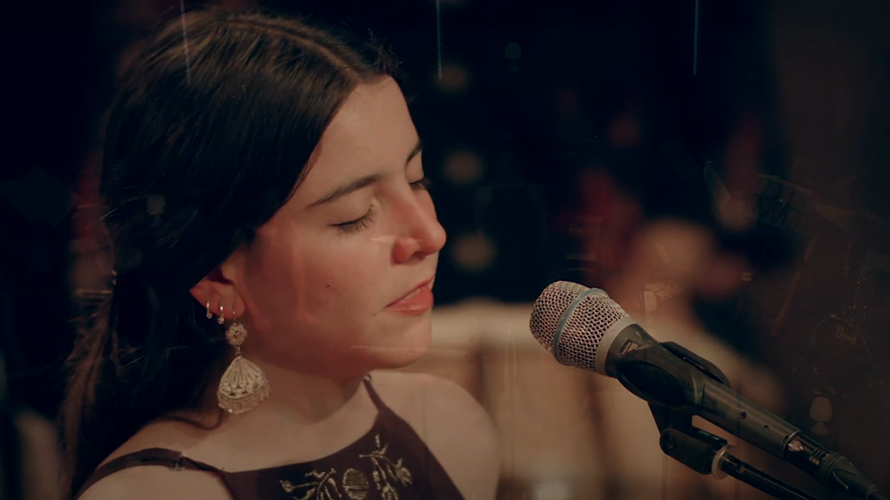 mexican female singer with golden earings singing into a microphone on stage for a live recording