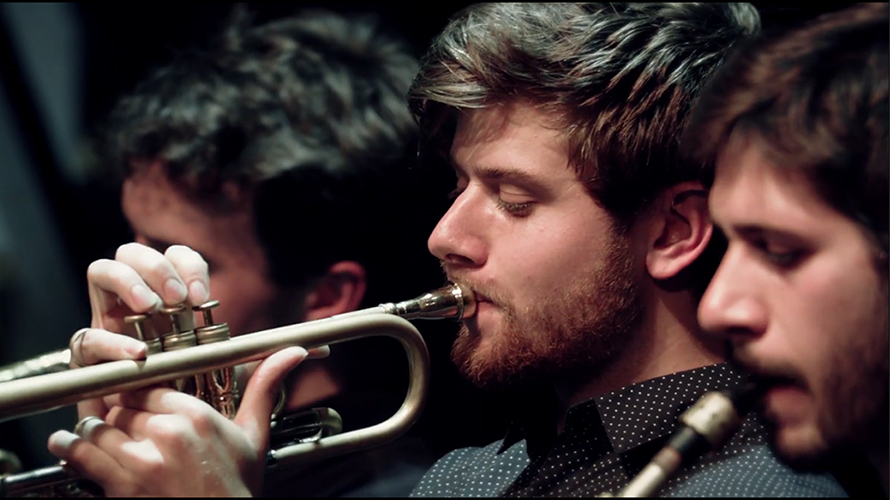 a band with a horn section performing live on the stage of the jazz club