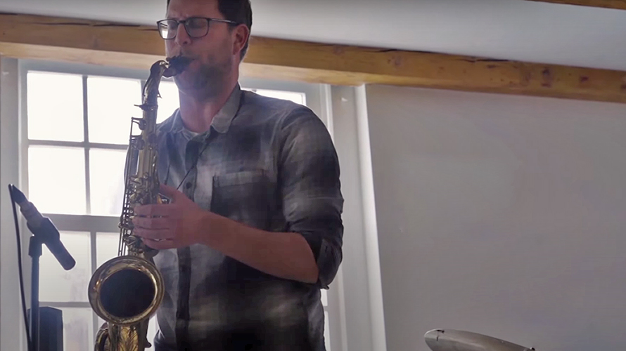 a band with a saxophonist playing at a house concert in a room overlooking westerkerk
